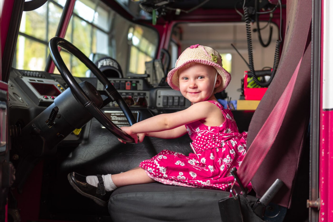 girl-sitting-in-fire-truck-smiling